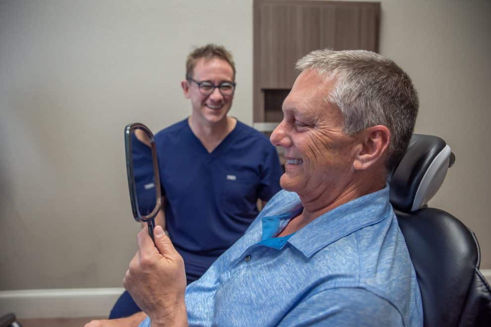 dentist with a patient looking at his new teeth after receiving dental implants in benbrook, tx